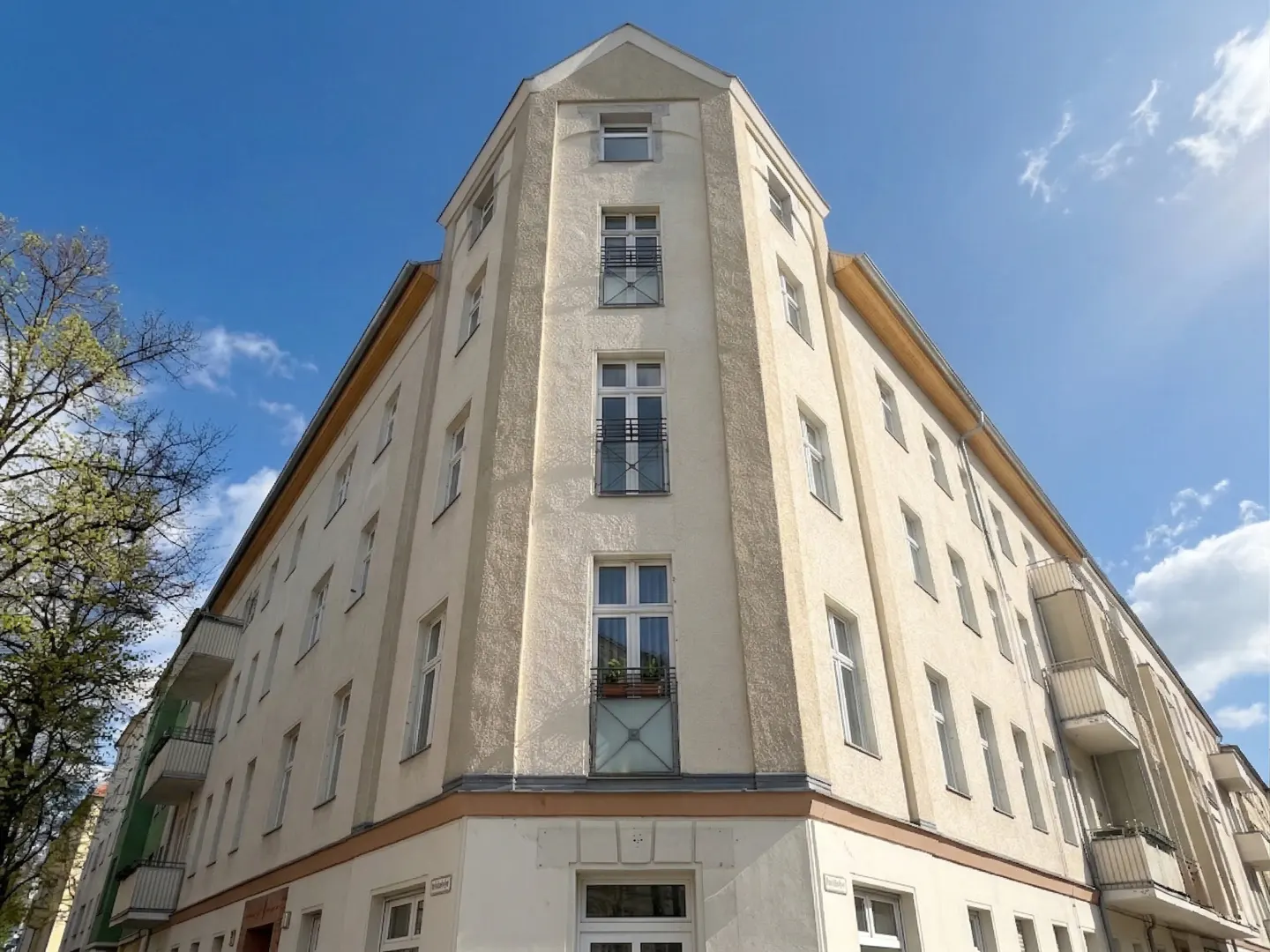Exterior view of a multi-story apartment building with white walls and windows under a blue sky.