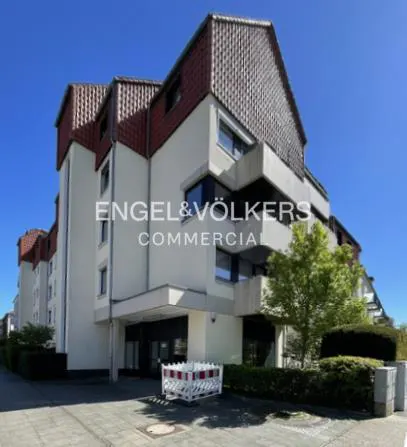 Exterior view of a multi-story commercial building with red roofs and an Engel & Völkers sign.
