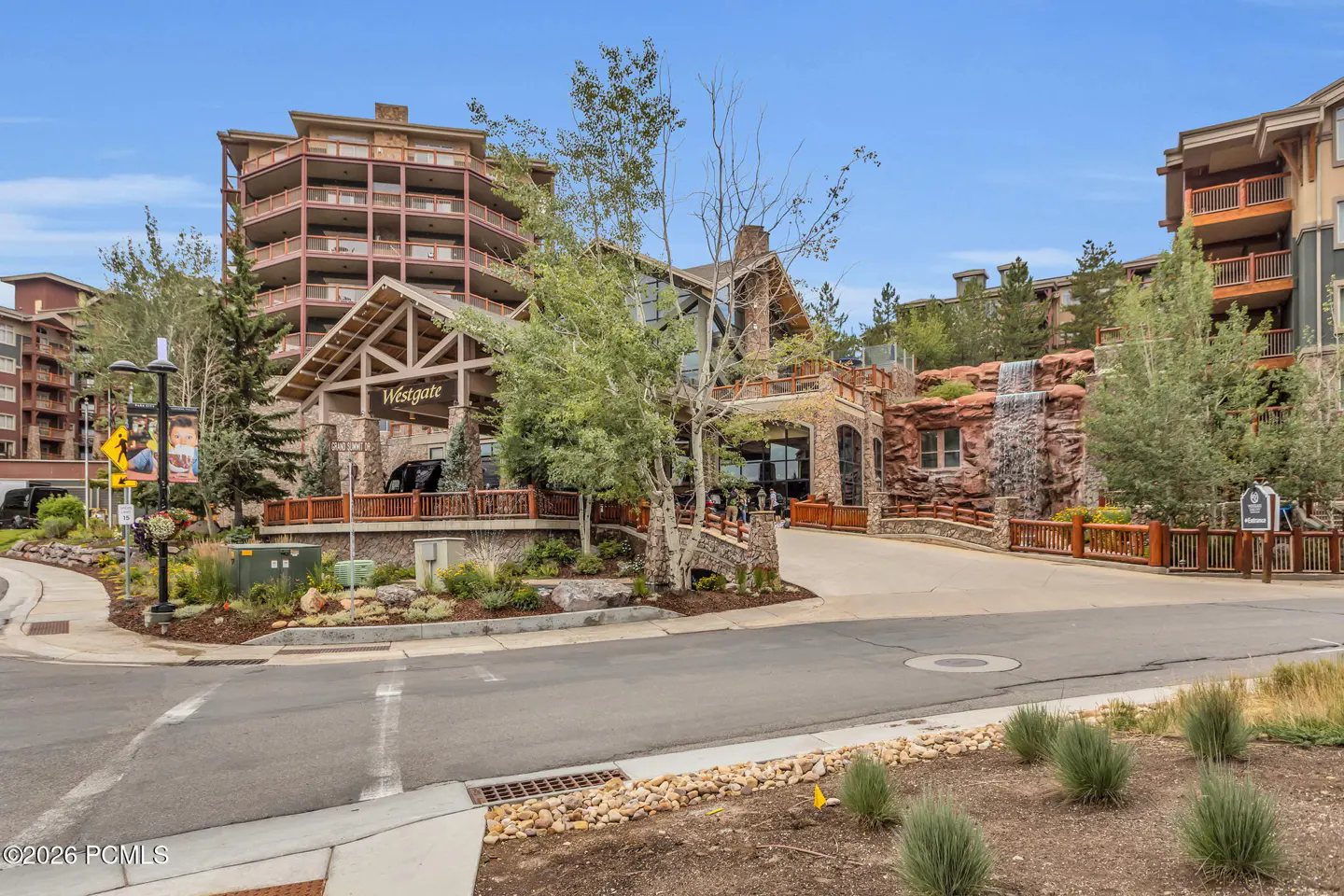 Exterior view of the Westgate resort featuring a stone building, a cascading waterfall, and a paved driveway under blue sky.