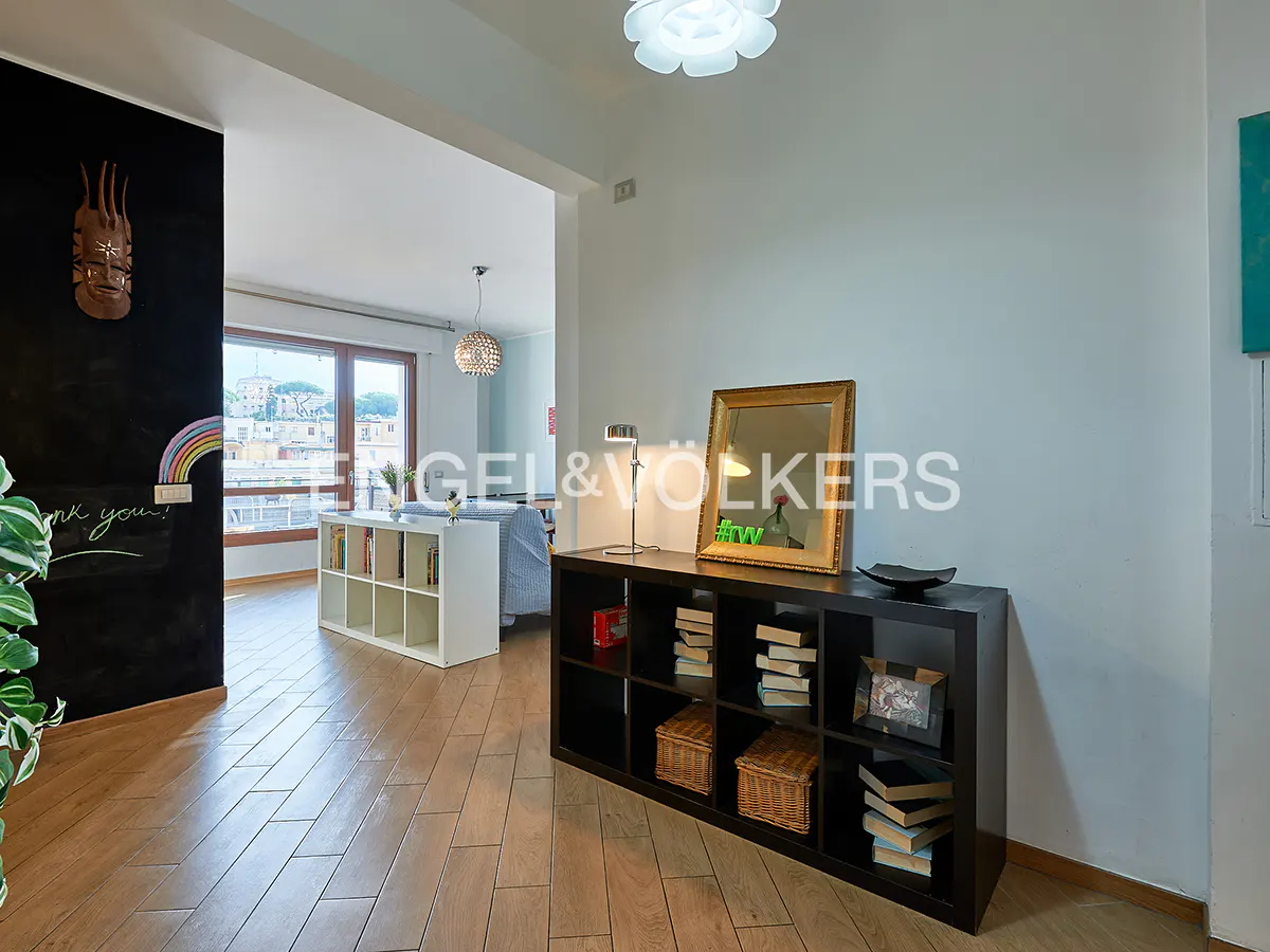 Interior view of a living room with a black bookshelf, mirror, and wooden floors. A chalkboard wall features a rainbow drawing.
