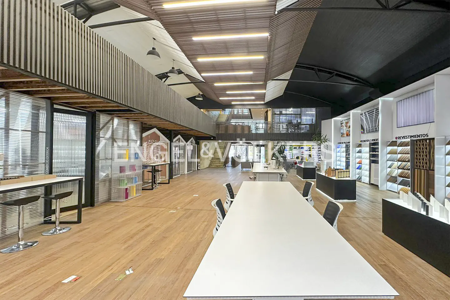 Engel & Völkers office interior with a large white table, wood floors, and displays of building materials.