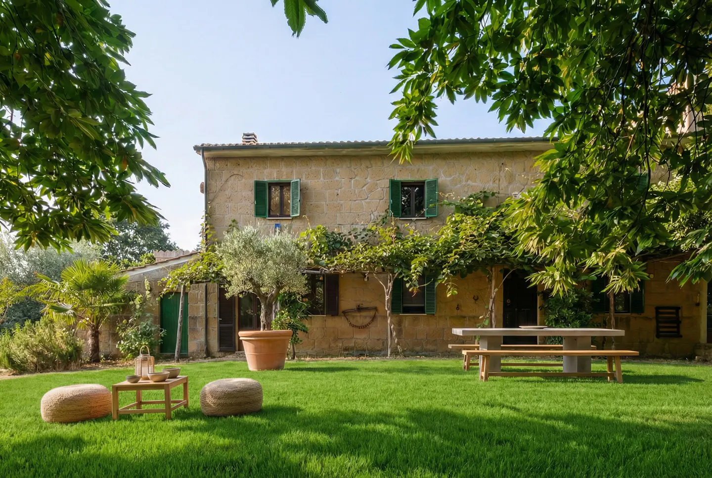 Exterior of a stone house with green shutters, a green lawn, and outdoor seating.