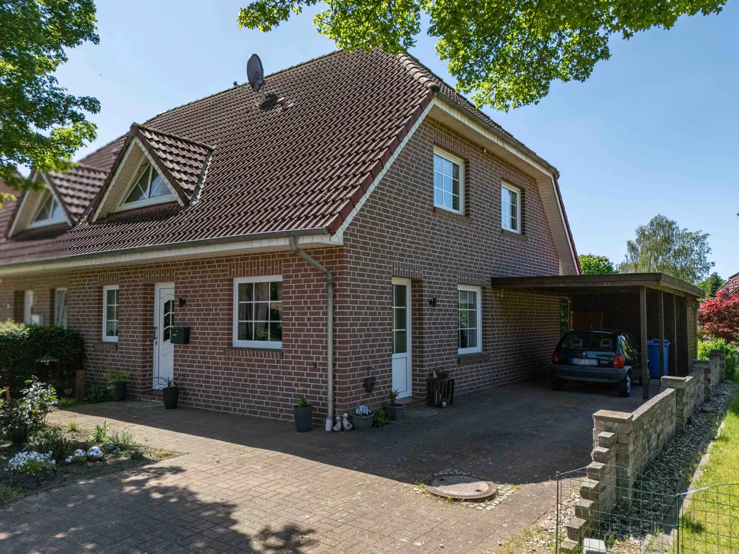 Two-story brick house with a brown roof and white trim, a carport, and a brick driveway.