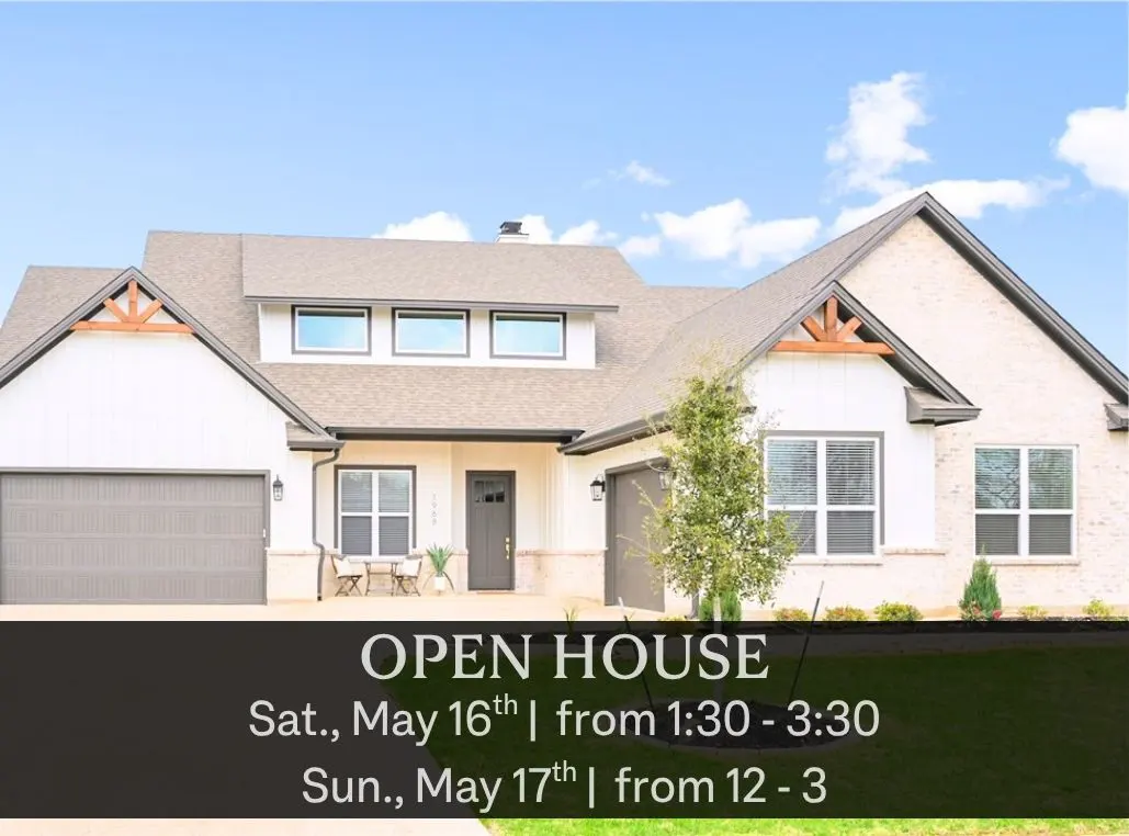 Two-story house with white siding, brick accents, and a gray roof under a blue sky. Open house banner in the foreground.