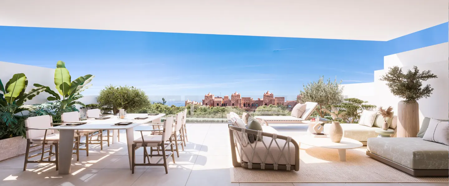 Outdoor patio with dining table, lounge seating, and a view of a red castle under a blue sky.
