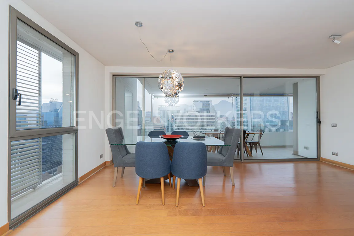 Modern dining room with glass table, four blue chairs, and a spherical pendant light, overlooking a city skyline.