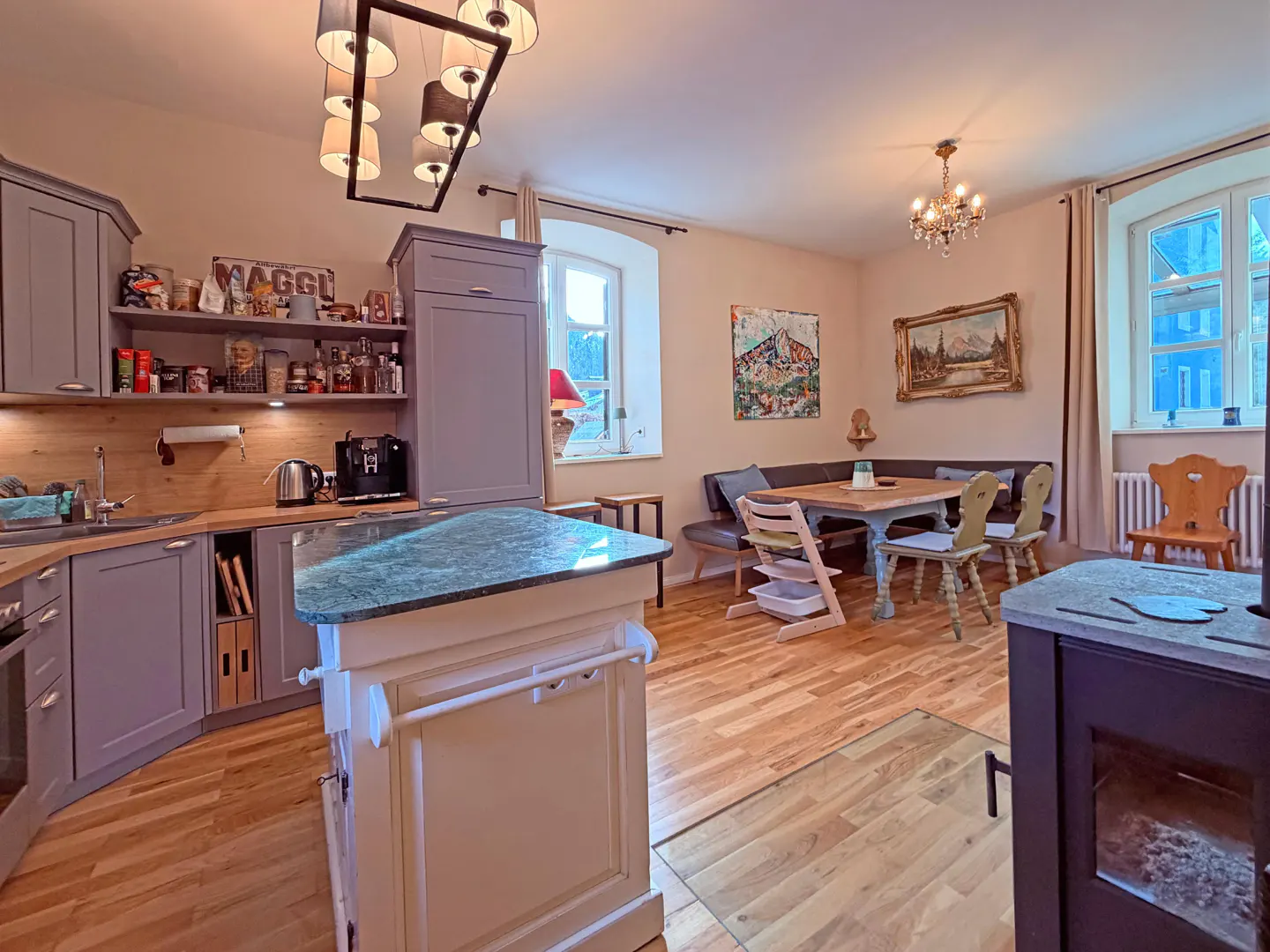A kitchen and dining area with gray cabinets, wood floors, and a dining table with chairs.
