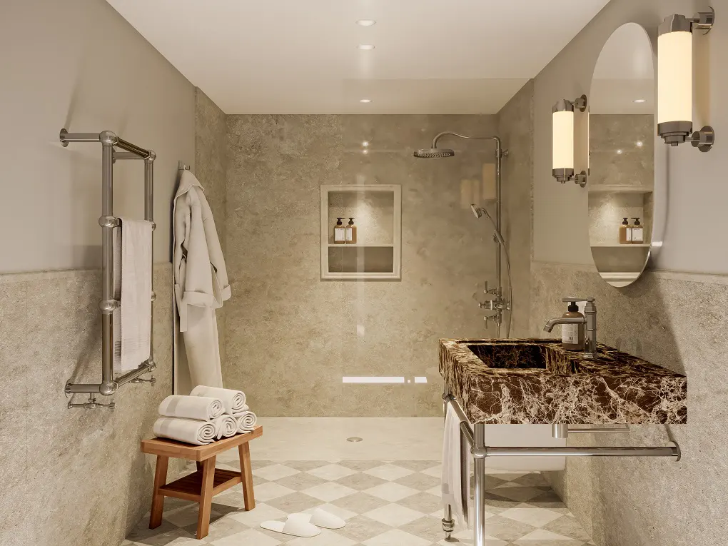 Modern bathroom with marble sink, silver fixtures, and a walk-in shower. A white robe hangs next to a wooden stool with rolled towels.