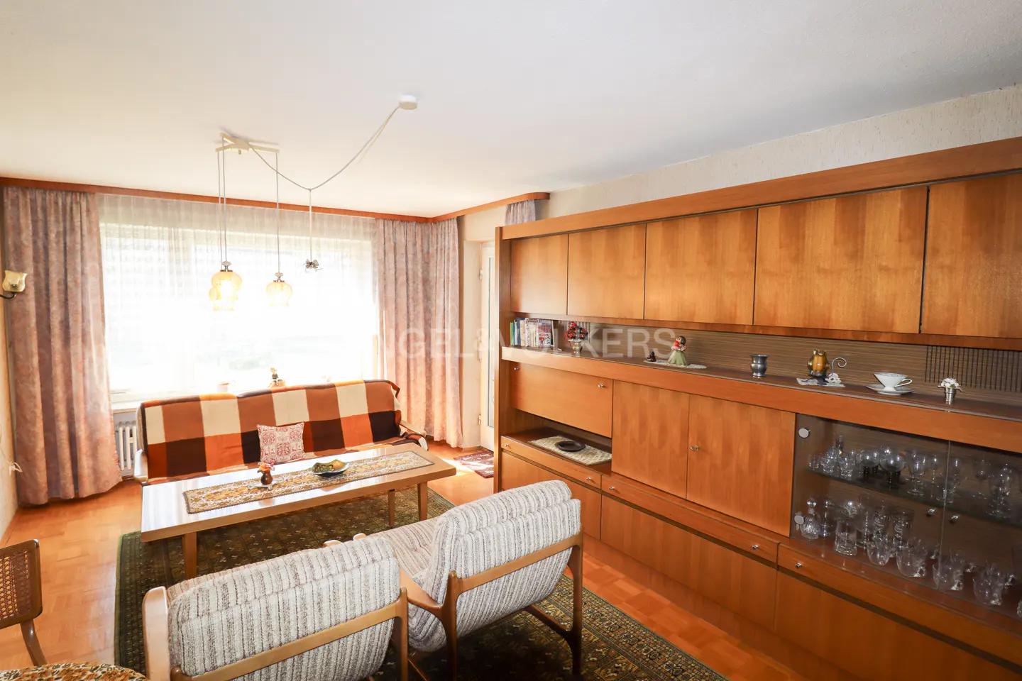 Living room with a brown plaid sofa, coffee table, and built-in wooden cabinets with glass display.