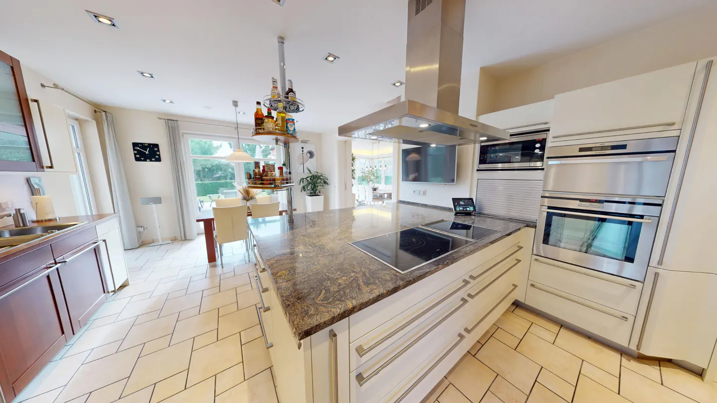 A modern kitchen with a large island, stainless steel appliances, and light-colored cabinets.