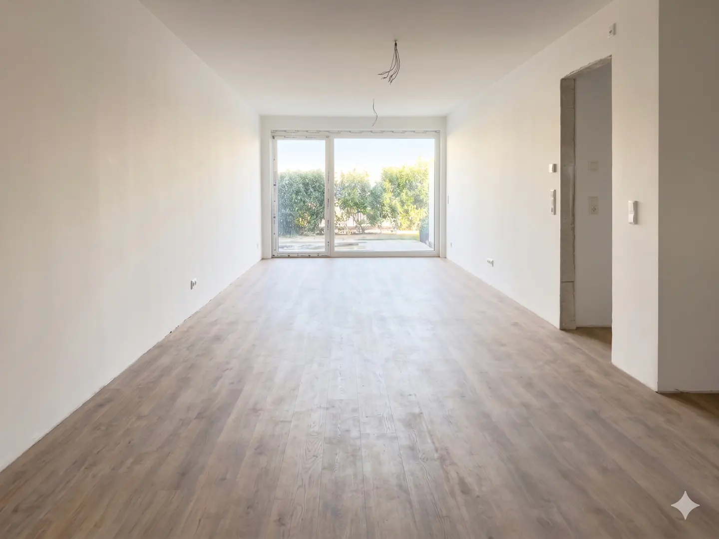 Unfurnished room with light wood floors, white walls, and a large sliding glass door to a green yard.