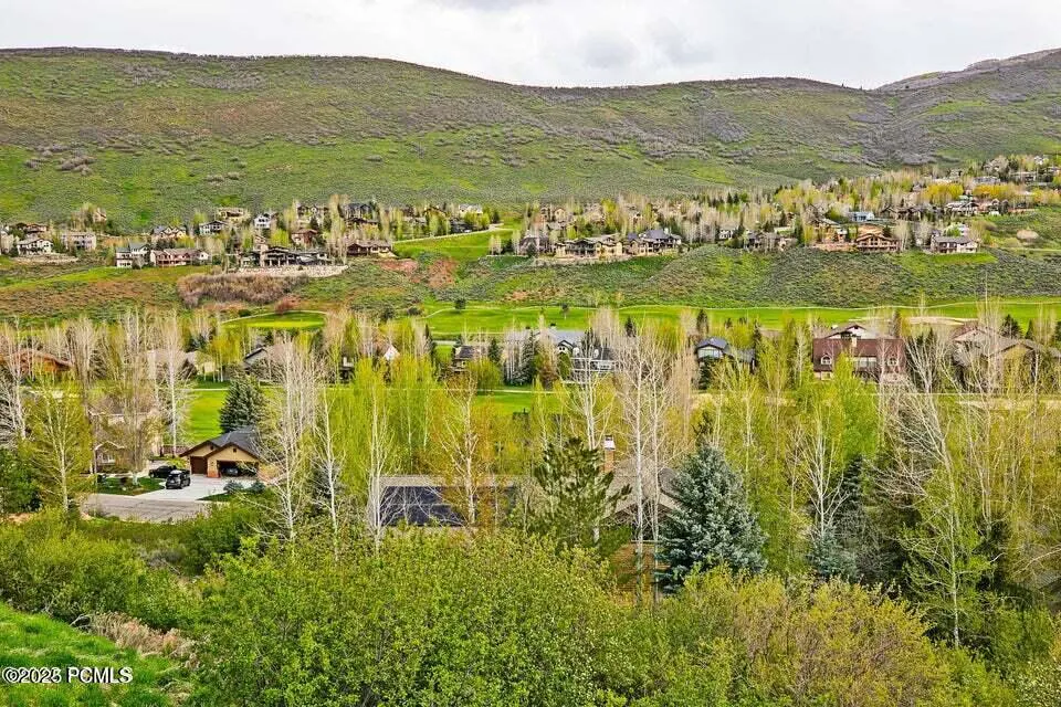 Scenic view of homes nestled in a green valley, with a lush, grassy hillside in the background.