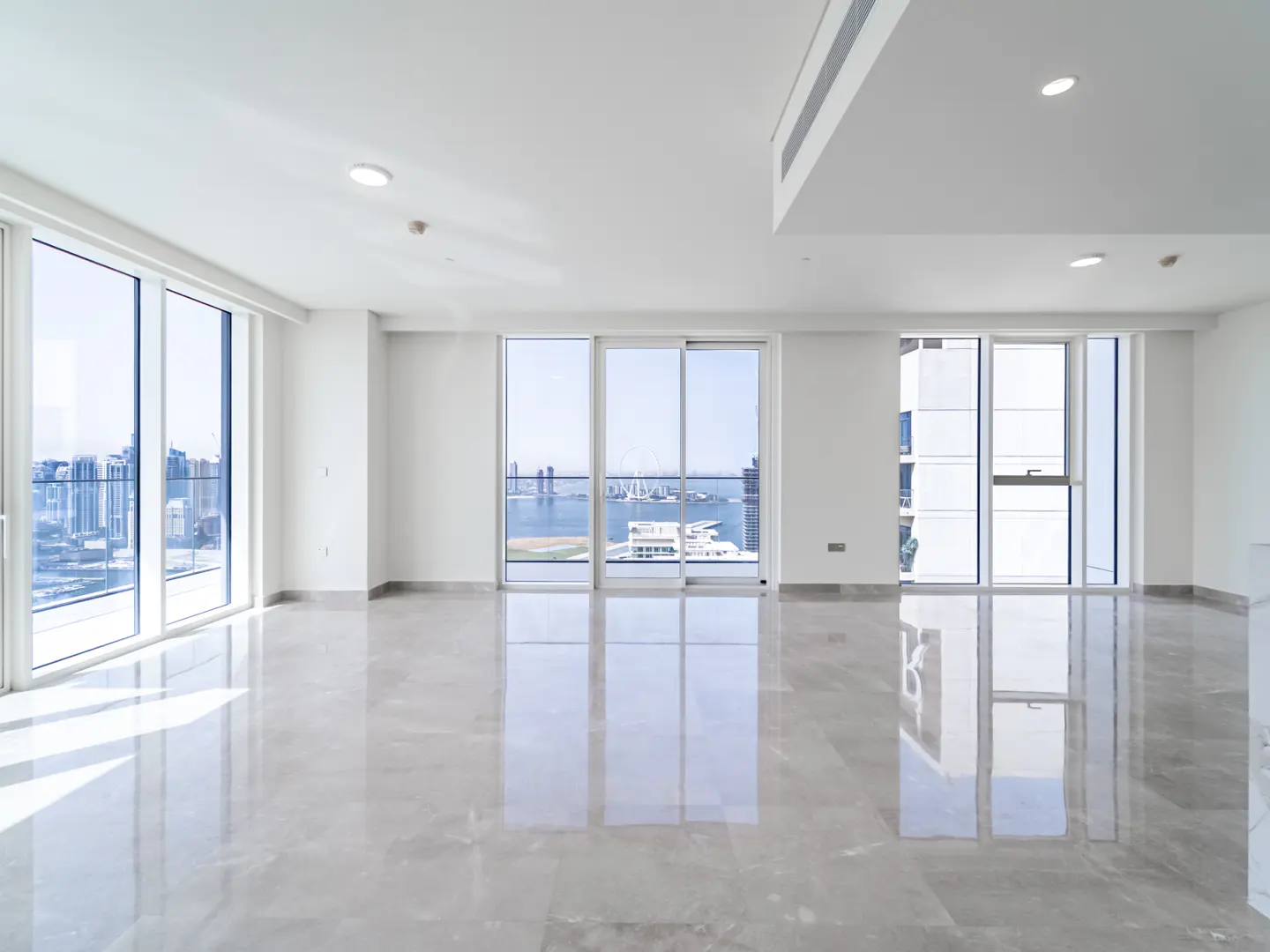 Bright, empty modern apartment with white walls, polished marble floors, and floor-to-ceiling windows overlooking a city.