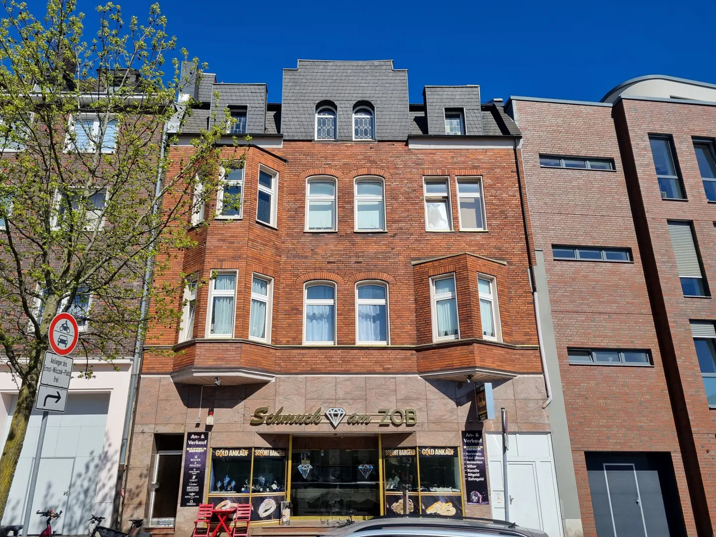A three-story brick building with a jewelry store on the ground floor, under a clear blue sky.