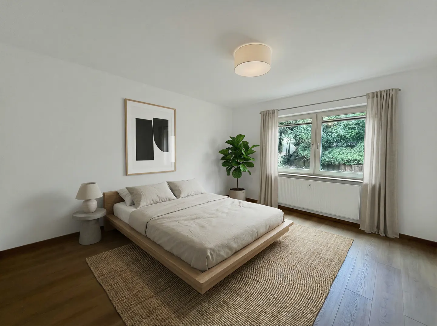 Bright bedroom with a low platform bed, beige linens, and a jute rug. A large window overlooks greenery, and a modern art piece hangs on the white wall.