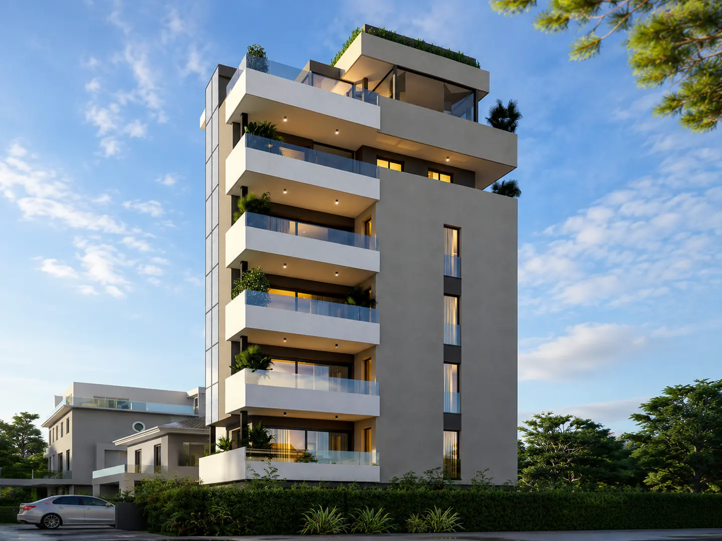 Modern gray apartment building with white balconies and glass railings, set against a blue sky with trees.