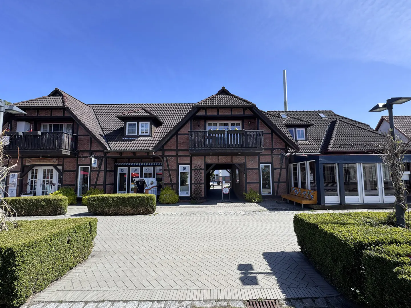 Exterior view of a brick building with black trim, a dark roof, and a central archway, under a clear blue sky.