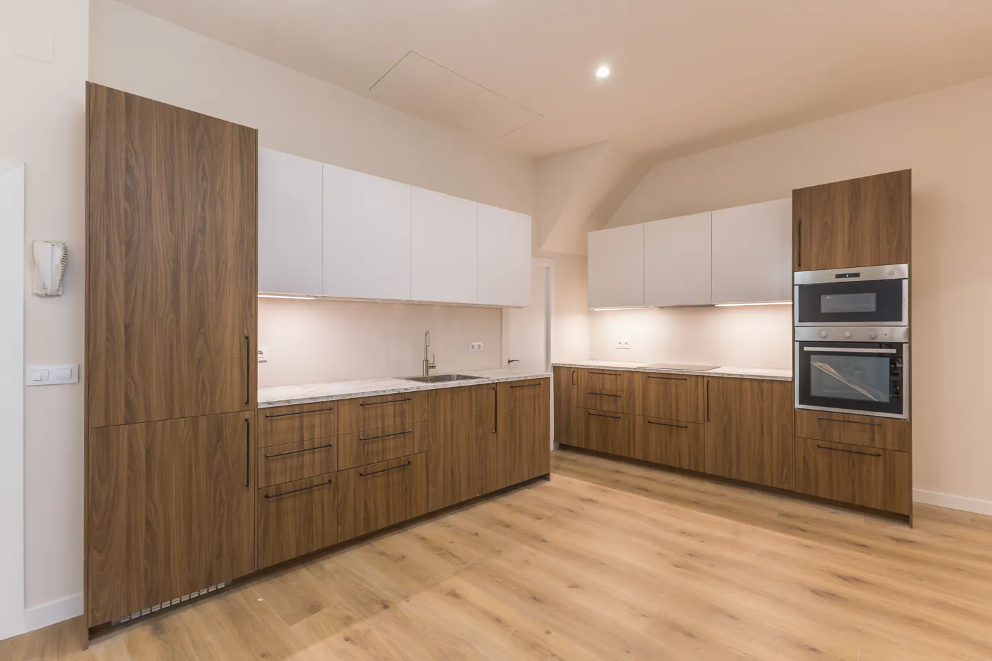 A modern kitchen with wood cabinets, white countertops, and stainless steel appliances.