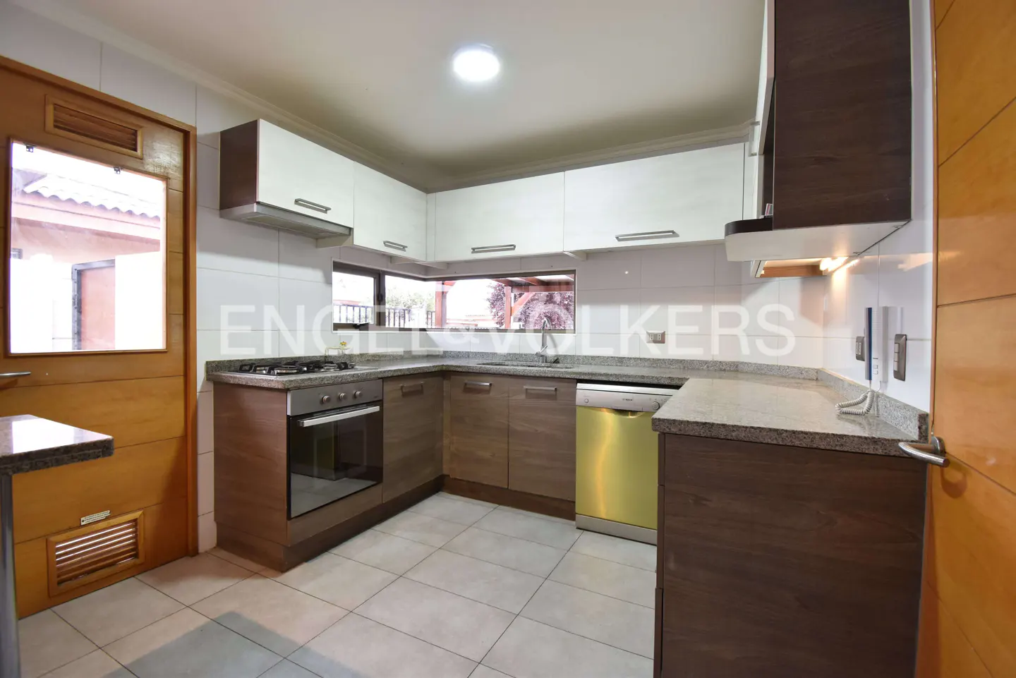 A kitchen with white and brown cabinets, stainless steel appliances, and a window overlooking the backyard.