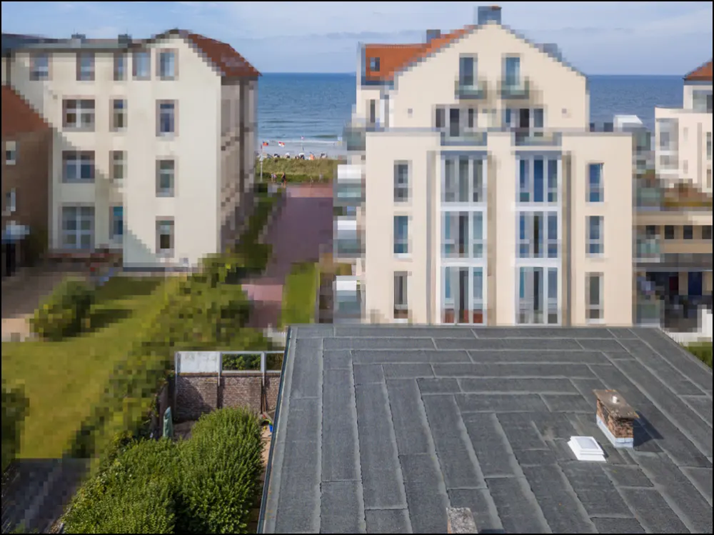 View from a rooftop of beige buildings near the ocean under a blue sky.