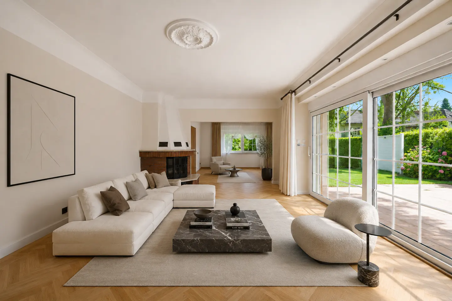 Bright living room with a white sectional sofa, marble coffee table, and a fireplace. Sliding glass doors open to a green lawn.