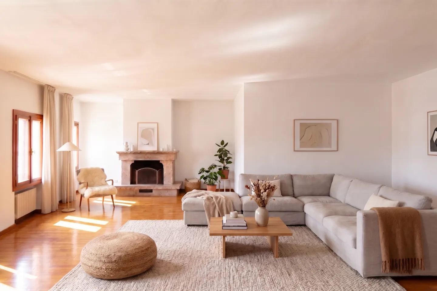 Bright living room with hardwood floors, a stone fireplace, and a large gray sectional sofa on a textured rug.