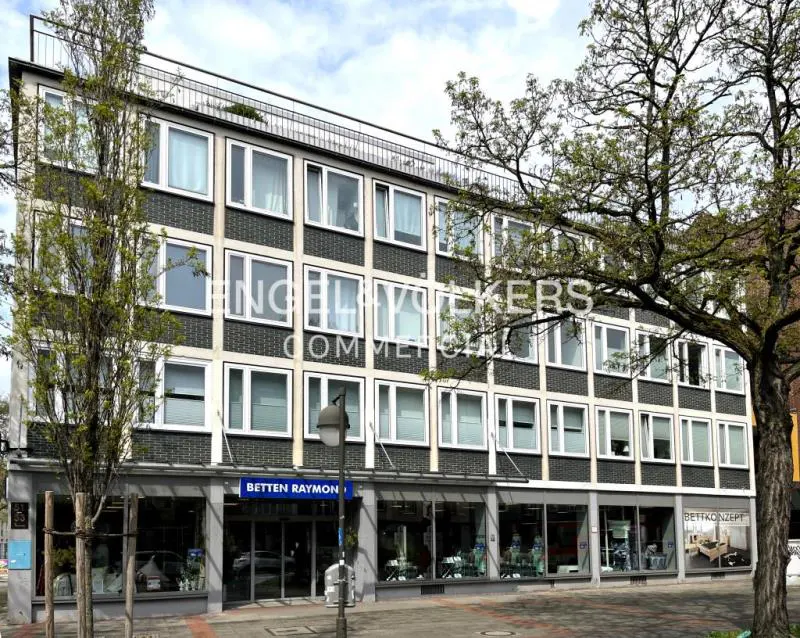 Exterior of a multi-story commercial building with "Betten Raymond" storefront and Engel & Völkers logo.