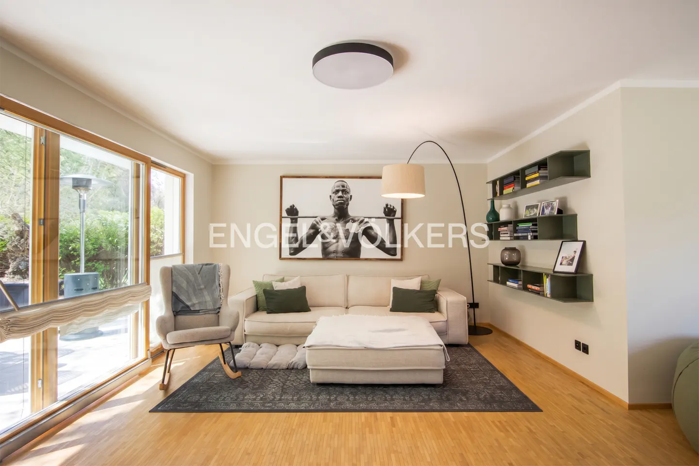 Living room with a white sofa, ottoman, rocking chair, and a black and white photo above the sofa.
