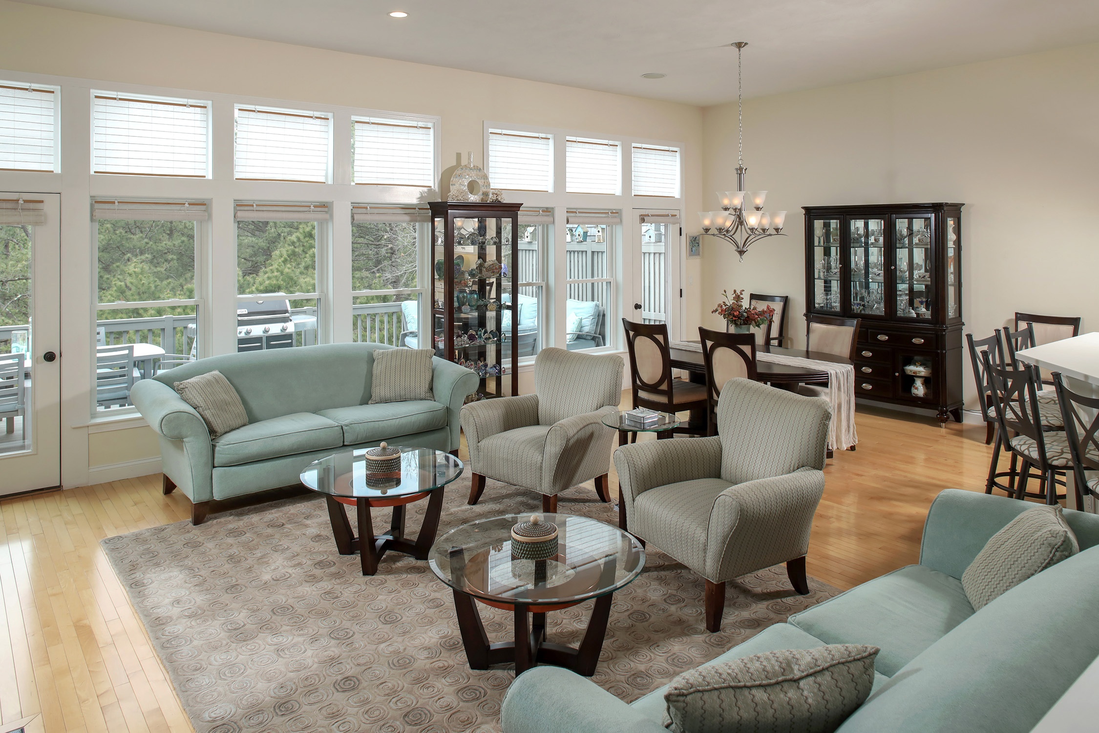 Spacious open-concept living and dining room with light blue sofas, patterned armchairs, and hardwood floors. [AI-generated text]