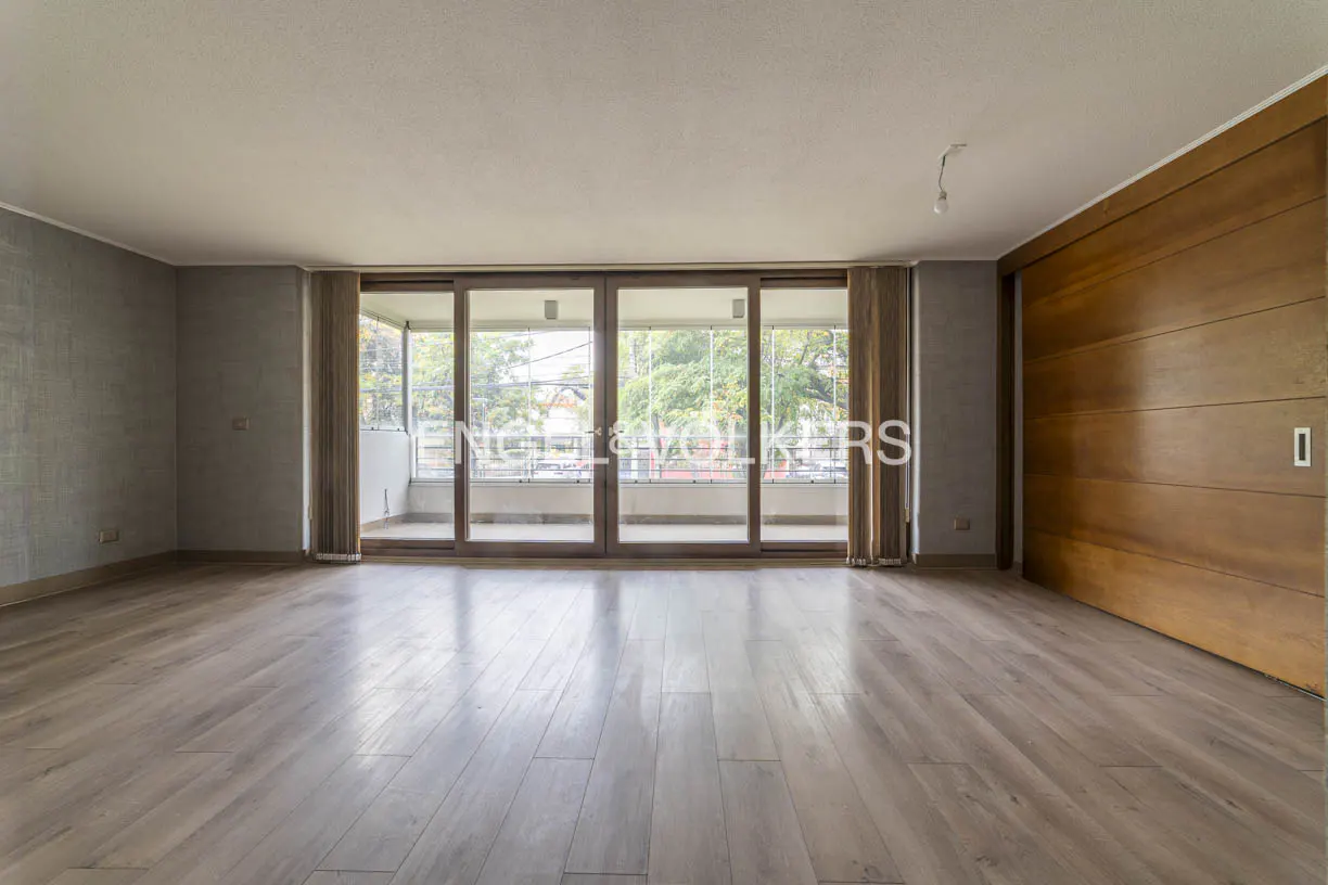 Empty living room with wood floors, gray walls, and sliding glass doors to a balcony. A large wood sliding door is on the right.