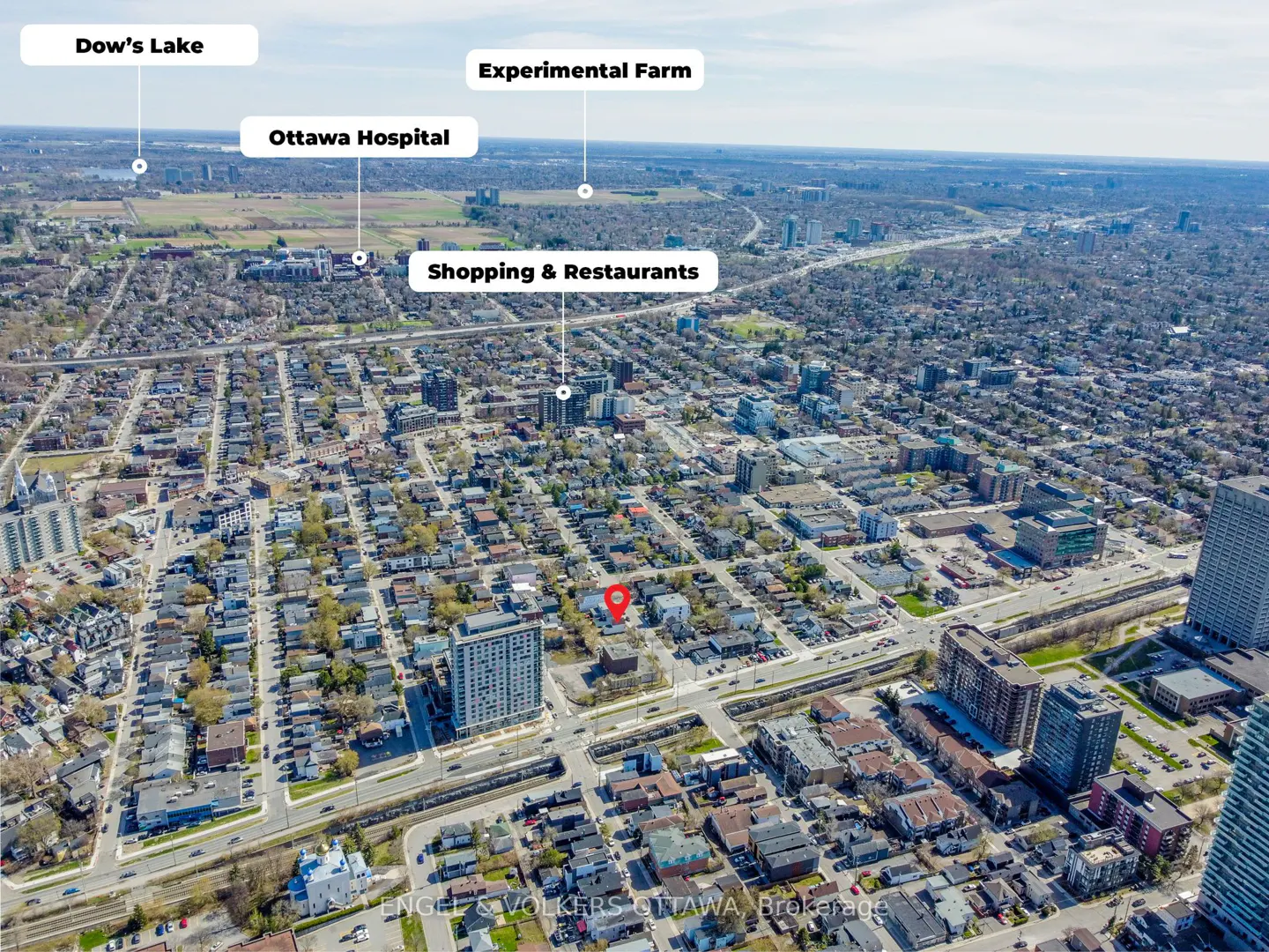 Aerial view of Ottawa neighborhood with houses, apartments, and businesses under a blue sky. A red pin marks a property location.