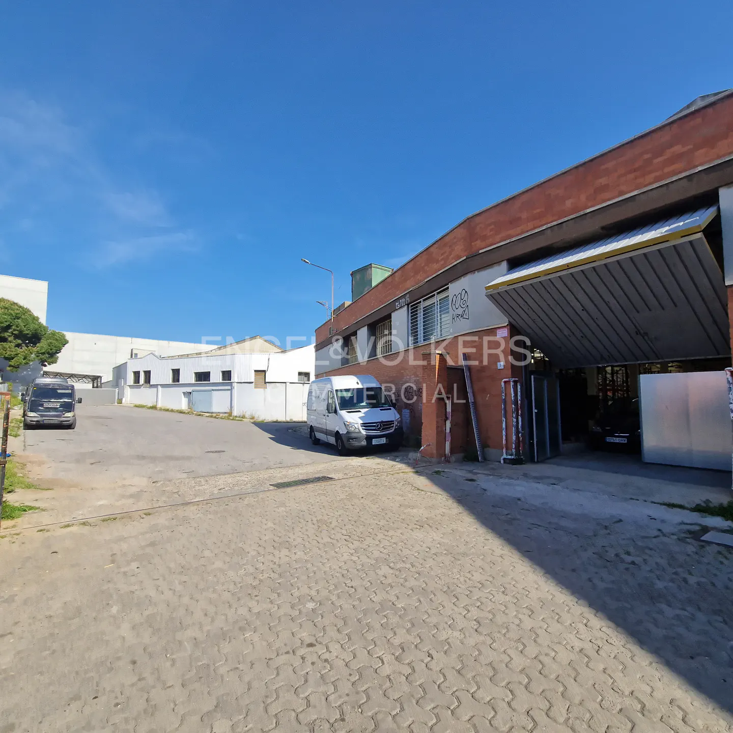 Exterior view of a commercial building with a white van parked outside, under a clear blue sky.