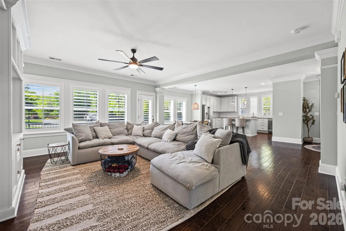 Spacious open-concept living room with a large grey sectional, round coffee table, and dark hardwood floors.