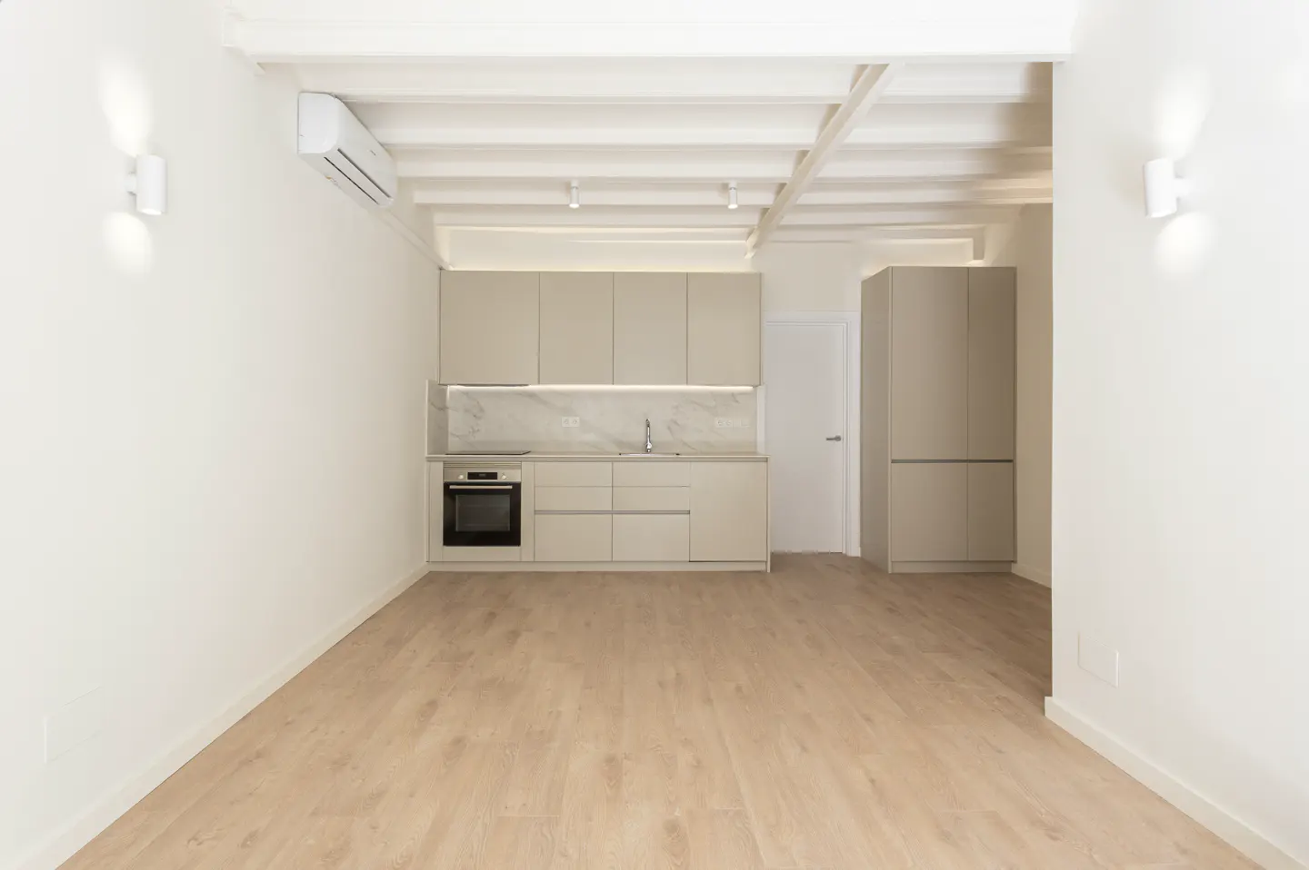 Modern minimalist kitchen with beige cabinets, marble backsplash, light wood floors, and white exposed beam ceiling.