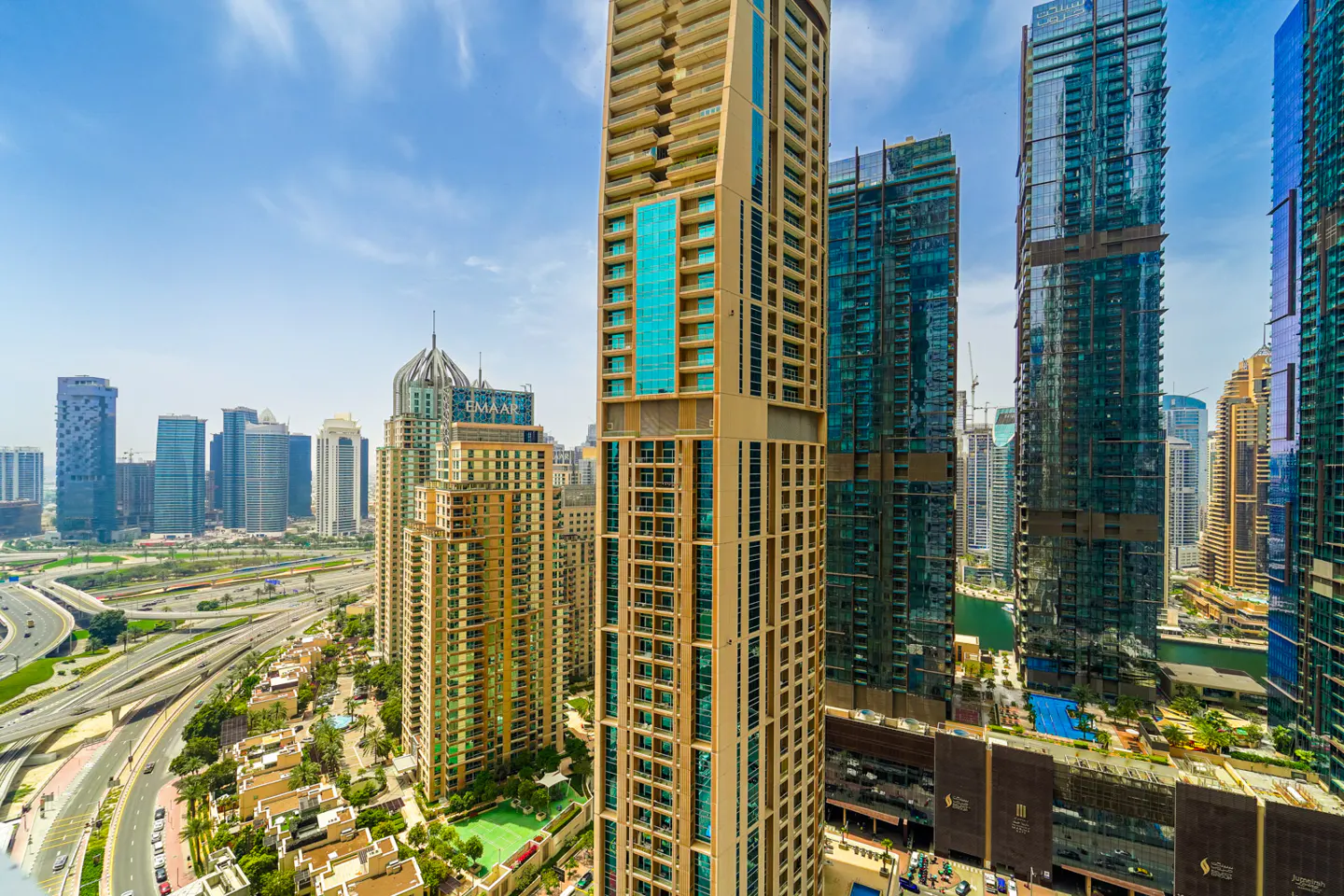View of Dubai's skyline with modern high-rise buildings, highways, and blue sky.