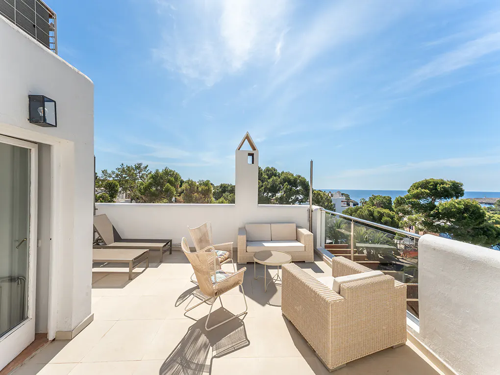 Bright, sunny rooftop patio with wicker furniture, lounge chairs, and ocean views.