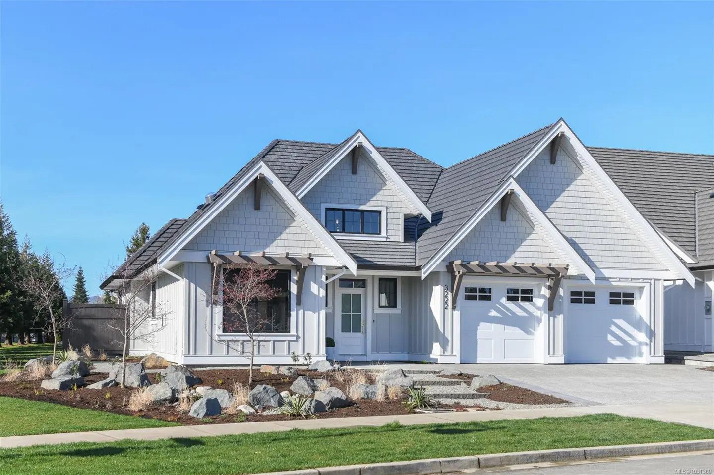 Exterior of a light gray house with a gray roof, white trim, and a two-car garage on a sunny day.