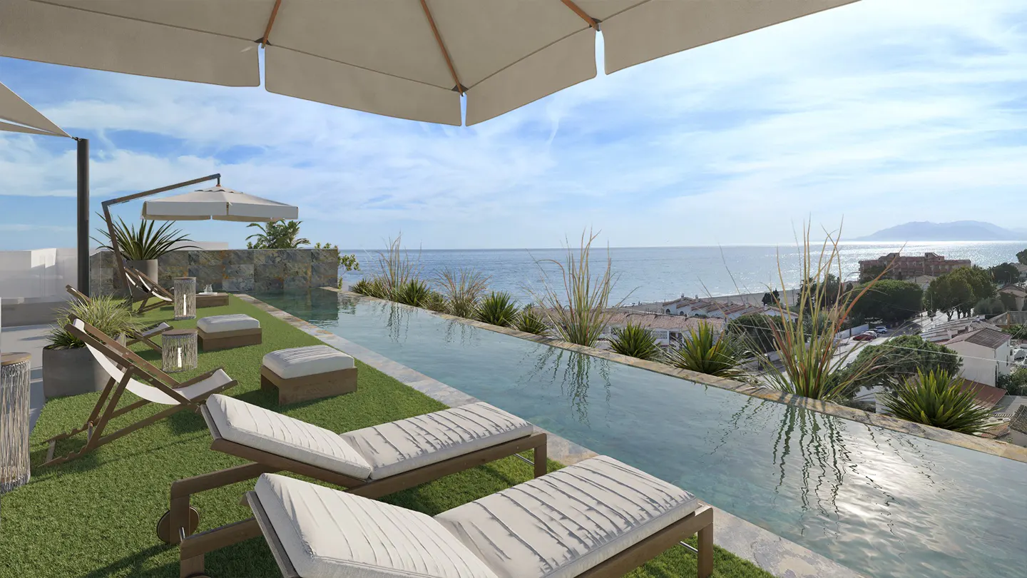 Infinity pool overlooking the ocean, with lounge chairs, umbrellas, and green grass.