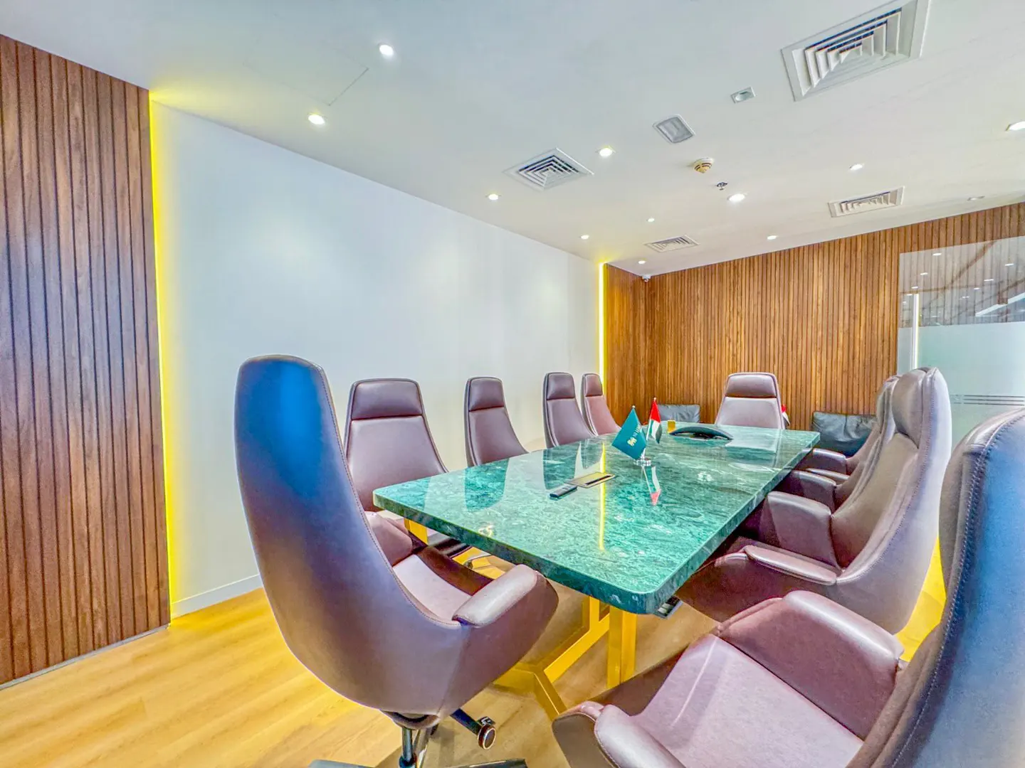 Conference room with a green marble table, brown leather chairs, and wood-paneled walls.