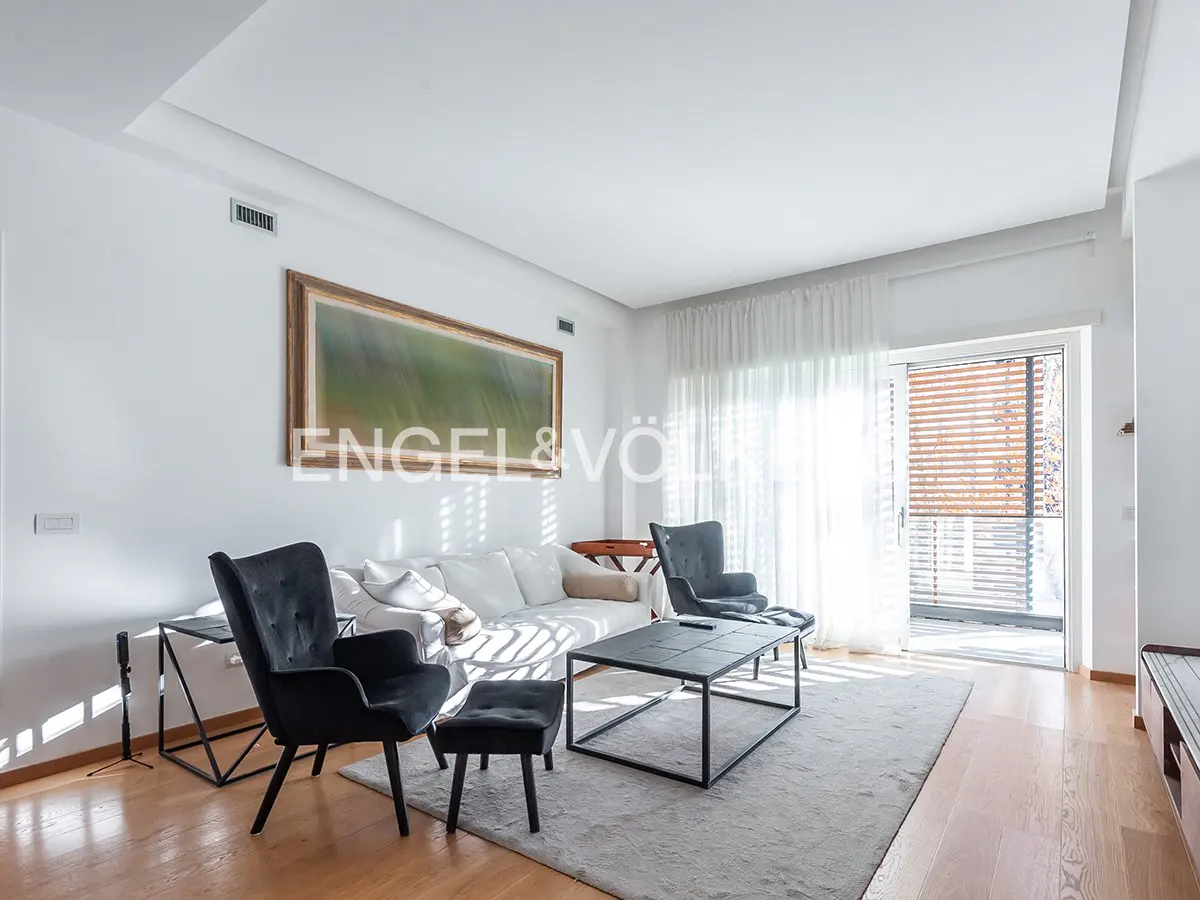 Modern living room with white sofa, two black armchairs, coffee table, and large abstract art on a white wall.
