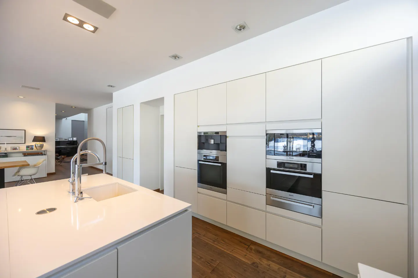 Bright, modern kitchen with white cabinets, stainless steel appliances, and a large island with a sink. Hardwood floors add warmth.