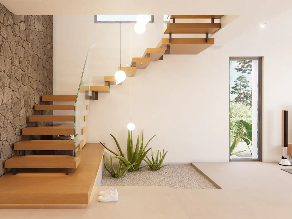 Modern home interior with floating wood stairs, glass railing, and stone accent wall. Potted plants sit on a gravel bed under pendant lights.
