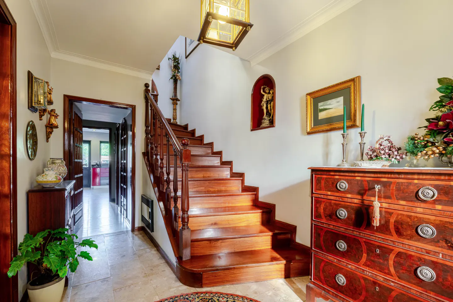 A foyer with a wooden staircase, a chest of drawers, and a doorway.