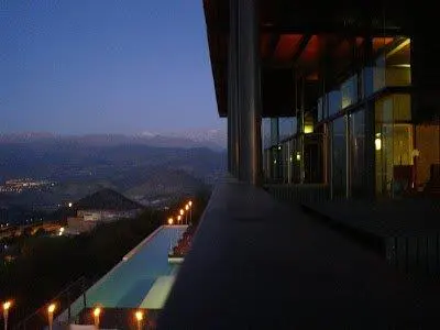 Twilight view of a modern house with a pool overlooking a valley and distant mountains.