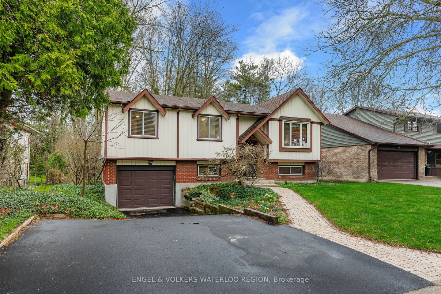 Exterior view of a two-story house with a brown garage door, brick accents, and a paved driveway.
