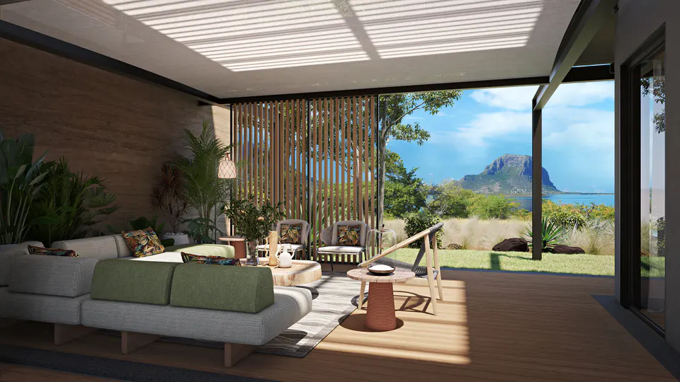 A bright living room with a gray sofa, green cushions, and a view of the ocean and mountain.