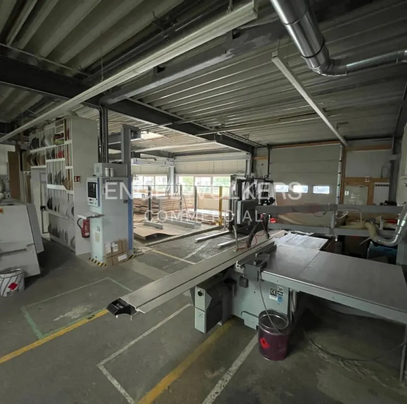 Interior view of a commercial space with industrial machinery, gray floors, and a high ceiling with metal beams.