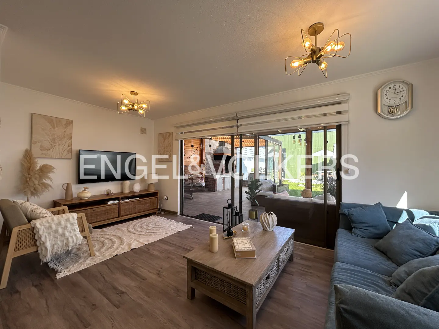 Modern living room with a blue sofa, wooden coffee table, TV console, and sliding glass doors opening to a patio.