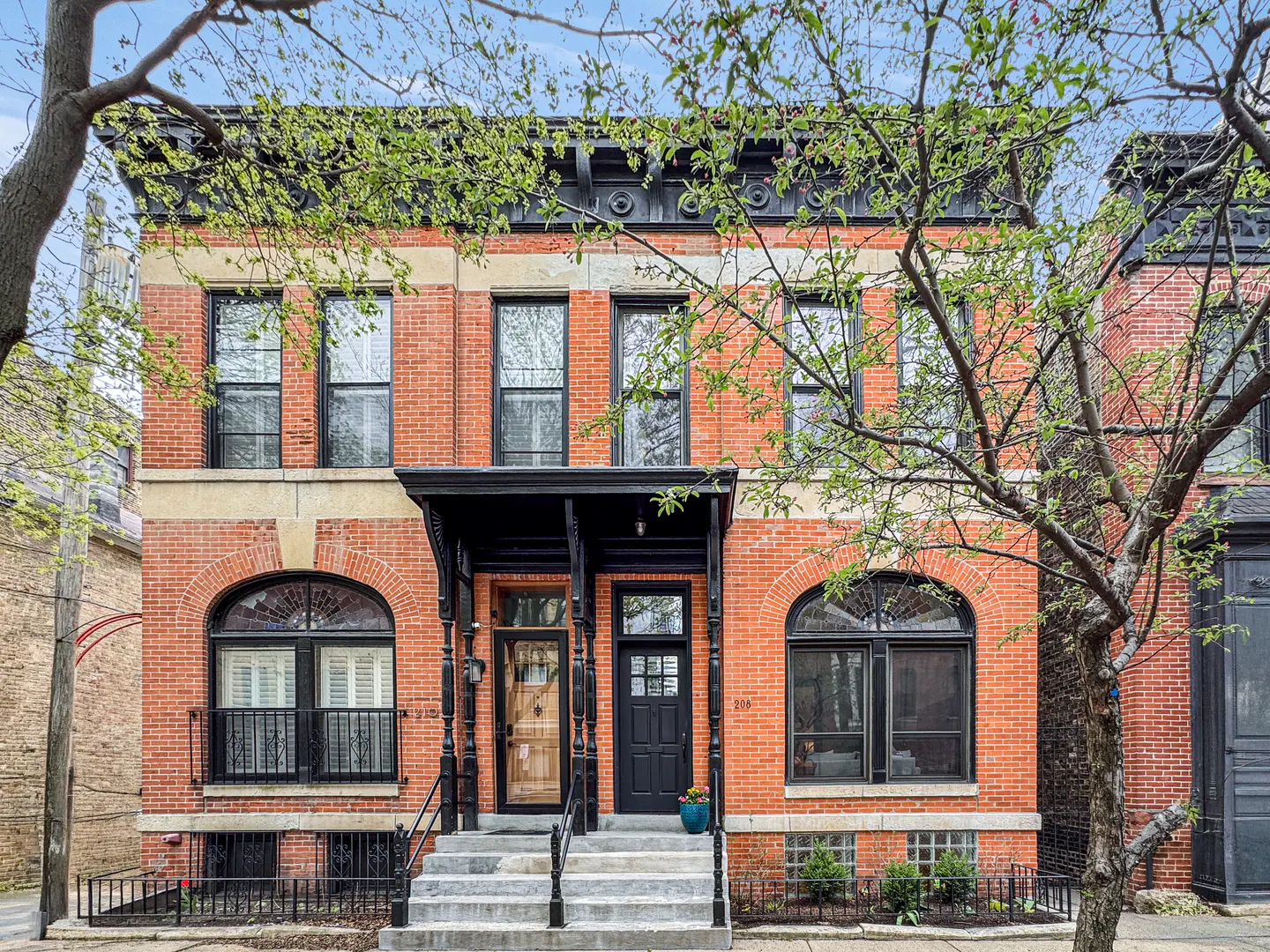 Red brick two-story duplex with black trim and arched windows. Concrete steps lead to the front doors.