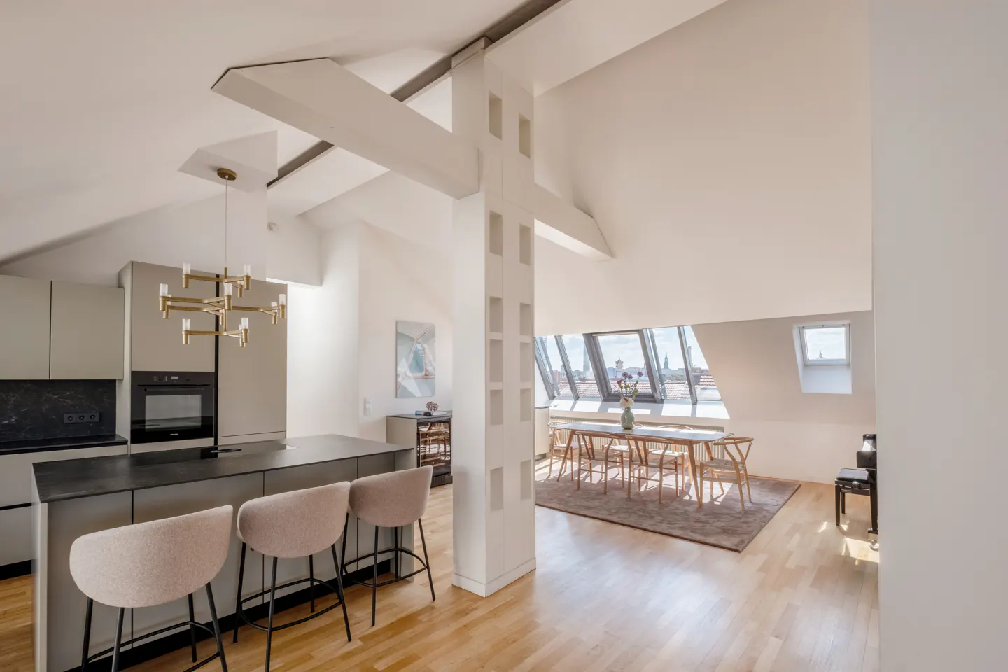 Open-concept kitchen and dining area with light wood floors. Island with three stools, dining table with city view.